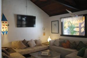 a living room with a couch and a tv at Aquarius Osteria in Arraial do Cabo