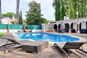 a swimming pool with two chairs and a deck with a patio at Verdizela Pool & Garden in Charneca +22 photos