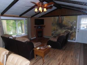a living room with two couches and a ceiling fan at Martin's River Cabin in Dresden