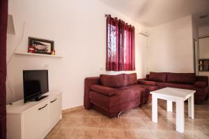 a living room with a couch and a tv at Flower Garden Villa in Ksamil