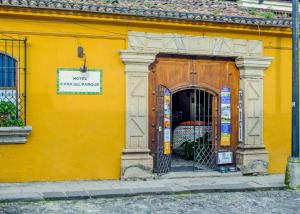 un edificio amarillo con una puerta con un cartel. en Hotel Casa del Parque by AHS, en Antigua Guatemala