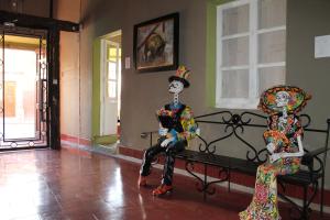 two clown statues sitting on a bench in a room at Hotel Galería in San Miguel de Allende