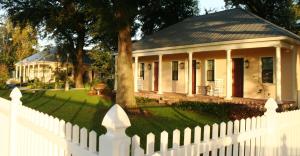 a white picket fence in front of a white house at The Inn at Houmas House Estate in Darrow