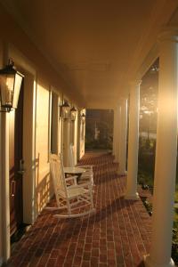 a porch with two chairs and a table on a house at The Inn at Houmas House Estate in Darrow