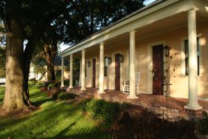 a white house with a porch and a tree at The Inn at Houmas House Estate in Darrow