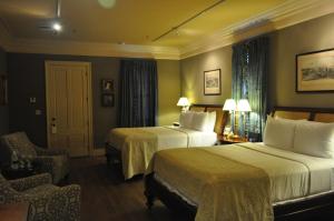 a hotel room with two beds and a chair at The Inn at Houmas House Estate in Darrow