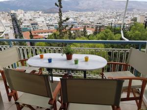 a table and chairs on a balcony with a view of a city at Park at Home Apartment in Athens