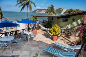 eine Terrasse mit Tischen und Stühlen und Meerblick in der Unterkunft POUSADA TIA LUCY in Natal