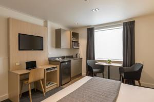 a hotel room with a bed and a kitchen and a table at Quest Dunedin Serviced Apartments in Dunedin