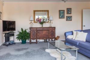 a living room with a blue couch and a mirror at The Whitehouse of Marybank in Nelson