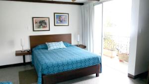a bedroom with a bed with a blue comforter and a window at Hotel del Oeste in Cali