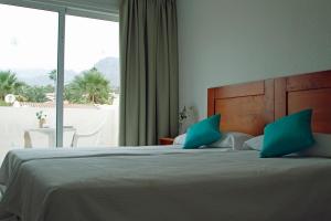 a bedroom with a bed with blue pillows and a window at Paradero II in Playa de las Americas