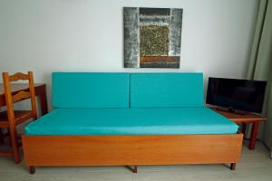a blue bed with a desk and a television at Paradero II in Playa de las Americas