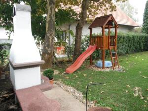 a playground with a slide and a swing set in a yard at Csokonai guesthouse in Zamárdi