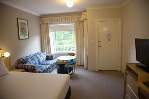 a hotel room with a bed and a chair and a window at Oxley Motel in Bowral