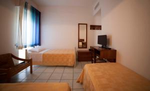 una camera d'albergo con due letti e una televisione di Hotel Nettuno a Soverato Marina
