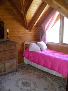 拉安戈斯圖拉鎮的住宿－La Casa de Huemul，卧室配有粉红色的床和窗户。