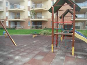 un parque infantil frente a un edificio con tobogán en Galerius Apartment, en Siófok