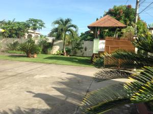 a house with a yard with a gazebo and palm trees at Danel Pensionne House in Tacloban