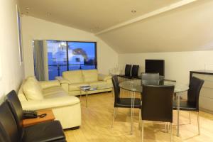BeachLife Apartments في كرايستشيرش: غرفة معيشة مع أريكة وطاولة وكراسي