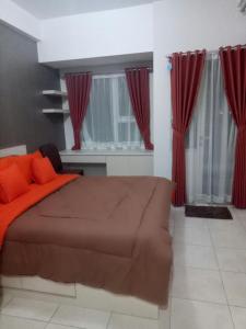 a bedroom with a bed with red pillows and curtains at Wjy Apartment Margonda Residence 5 in Depok