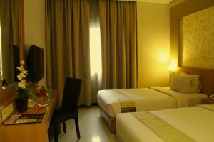 a hotel room with two beds and a desk at Drego Hotel in Pekanbaru