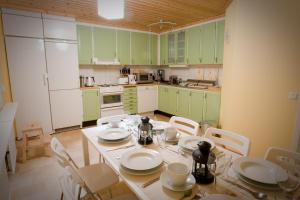 una cucina con armadi verdi, tavolo e sedie di Hogbacka Lodge ad Älvsbyn