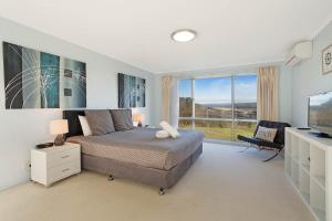 um quarto com uma cama e uma grande janela em Waterview Luxury Apartments em Merimbula