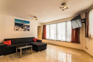 ein Wohnzimmer mit einer schwarzen Couch und einem Fernseher in der Unterkunft Villa Gastuna in Bad Gastein