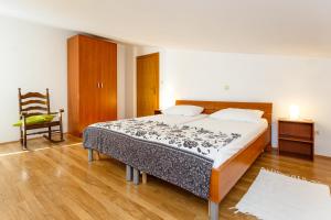 a bedroom with a large bed and a chair at Apartment Baldigara in Njivice