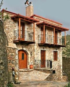 ein großes Steinhaus mit Balkon an der Seite in der Unterkunft Archontiko tis Zois in Stemnitsa