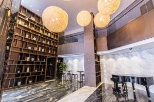 a lobby with a bar with stools and chandeliers at Green Court Residence Jinqiao Diamond Shanghai in Shanghai