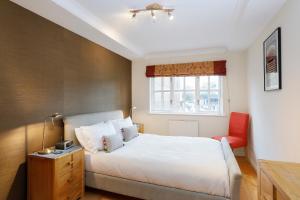 een slaapkamer met een wit bed en een rode stoel bij Calm 2BR apt with parking and patio, 15mins to London Eye in Londen