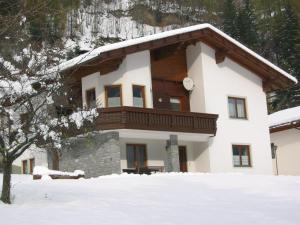 a house with a balcony on the front in the snow at Ferienwohnung Ebner in Flattach