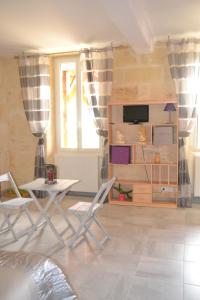 a living room with chairs and a table and a tv at Maison d'Hôtes La Prévôté in Périssac