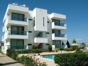 un edificio blanco con una piscina frente a él en Belek Golf Apartments, en Belek