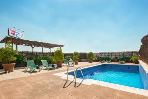 a swimming pool with chairs and a pergola at Ibis Granada in Granada