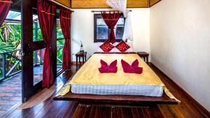 Un dormitorio con una cama con almohadas rojas. en Fruit Tree Lodge en Ko Lanta