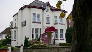 a large white house with a sign in front of it at Trivelles Belforte Hotel , Sale, Manchester - M33 2AE in Sale