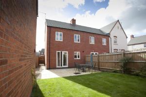 a brick house with a patio and a fence at DBS Serviced Apartments - The Stretton in Castle Donington