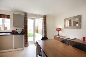 a kitchen with a table and a dining room at DBS Serviced Apartments - The Stretton in Castle Donington
