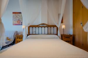 um quarto com uma grande cama branca com cortinas em Apartamento Levante em Conil de la Frontera