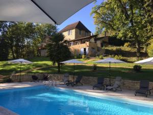 a swimming pool with chairs and umbrellas in front of a house at Au Coeur De Lolhm in Le Buisson de Cadouin