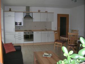 une cuisine avec des placards blancs et un salon dans l'établissement Ferienwohnung Familie Sinn, à Pappenheim