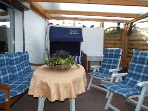 un patio con sillas y una mesa con un arreglo floral en Haus Ferienglueck _ Lueth en Friedrichskoog