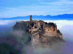 a castle on top of a mountain in the clouds at The Pinball Luxury Suites in Viterbo