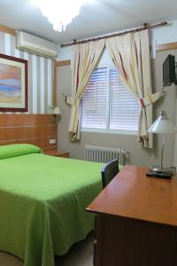 Un dormitorio con una cama verde y una ventana en Hostal Don Juan I, en Alcalá de Henares