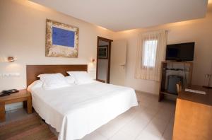 1 dormitorio con 1 cama blanca grande y TV en Hotel Cal Naudi, en Les Cases d'Alcanar