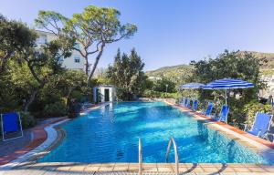 a swimming pool with blue chairs and an umbrella at Hotel Vittoria in Ischia