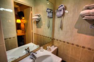 a bathroom with a sink and a tub and a mirror at Hôtel Des Trois Gares in Paris